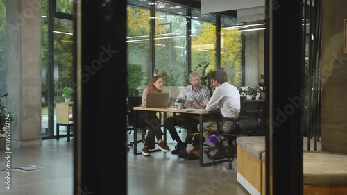 Business people in the office behind a glass partition in casual clothes, with blurred bokeh background.