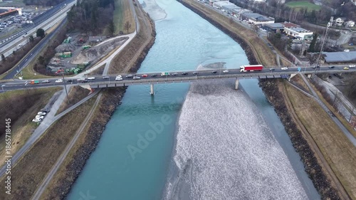 Aerial drone flight crossing the bridge over the Rhine between Liechtenstein and Switzerland, capturing cars in traffic as they leave Liechtenstein toward Switzerland, highlighting river, bridge, and 
