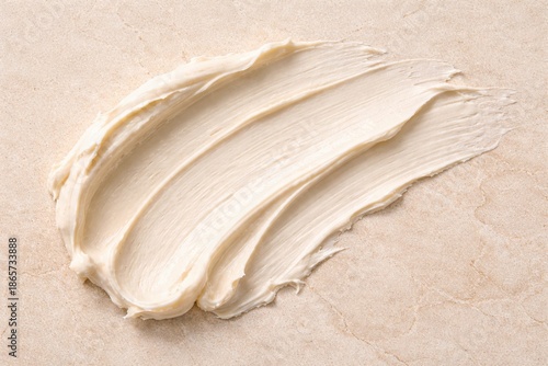 Elegant Swirl: An artistic smear of creamy substance gracefully rests, highlighting texture and form, a symphony of delicate lines and subtle shades on a smooth background.
