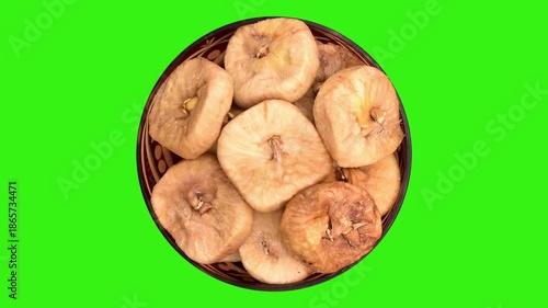 Dried figs in decorative glass bowl rotating on the green screen. Top view.