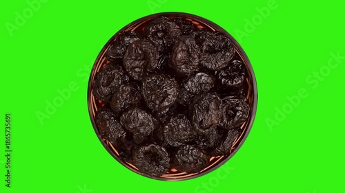 Dried plums or prunes in decorative glass bowl rotating on the green screen. Top view.