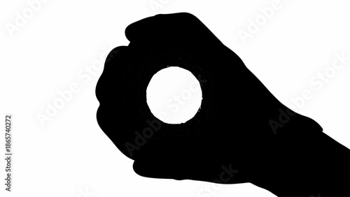 Silhouette of a hand holding a small white circle against a bright background, suggesting focus or a concept.