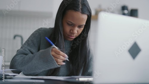 Work remotely in home office or learn online, black woman examining information. African american lady using laptop for education or distant job, pretty female student in home workplace, portrait