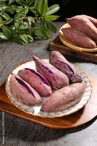 Fresh Purple Sweet Potatoes on Wooden Board with Herbs