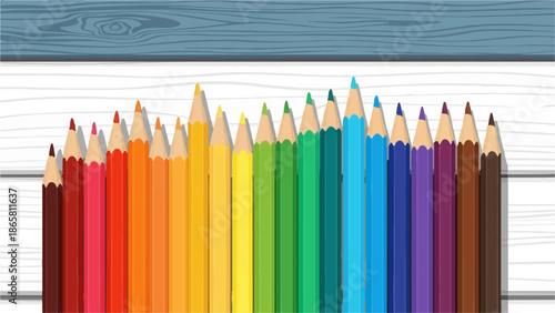 A rainbow of colored pencils arranged on a textured wooden surface