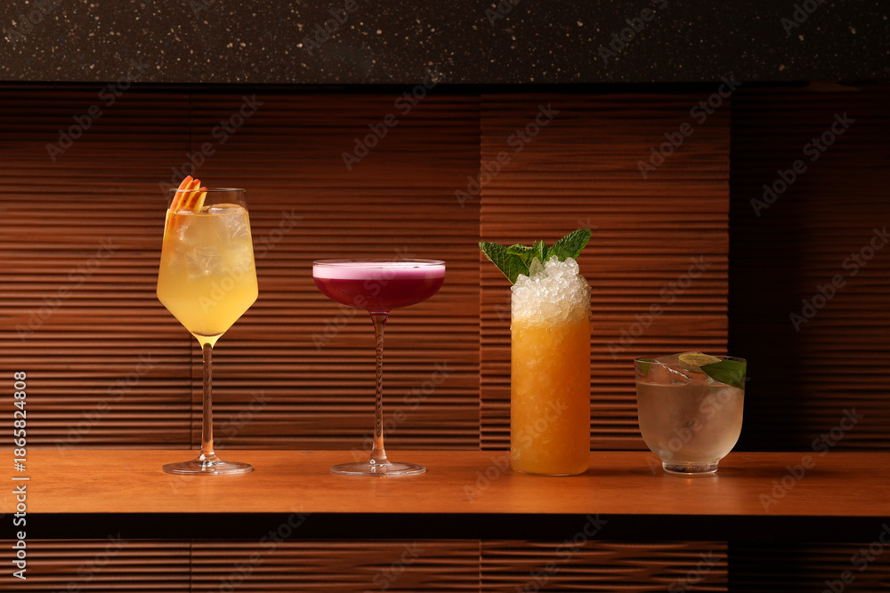 Naklejka premium Variety of Four Colorful Craft Cocktails on a Wooden Bar