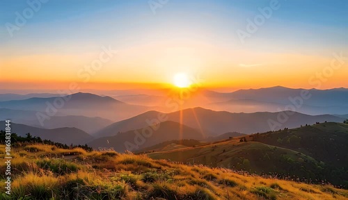 Golden Sunrise Over Misty Mountain Peaks With Dry Grass Foreground In Warm Golden Hour Light
