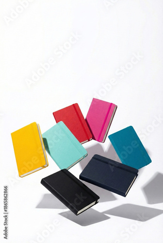 Seven colorful pocket notebooks floating in a circular arrangement on a white background.