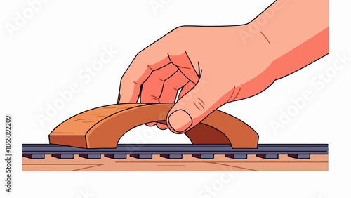 Hand shaping a wooden toy train bridge over tracks