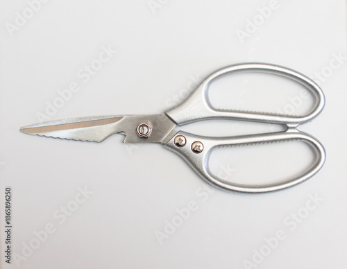 Stainless steel scissors are placed on a white surface.