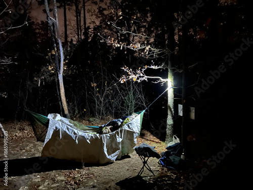 Hammock camp is softly lit in the middle of a dark forest, creating a sense of shelter and solitude