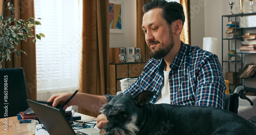 Фотография A smiling man in a white blouse and plaid shirt talks to his colleague about a new bank client impressed by the offer, while filling out final documents next to his open laptop
