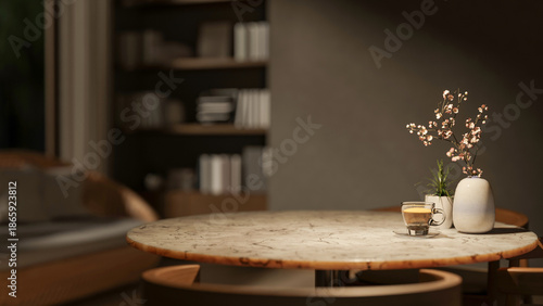 Foto Coffee cup with pot plant and flower vase on round marble table with sofa and bookshelf in dim room