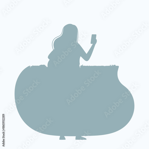 Silhouette of a woman sitting on a large rock while using a smartphone