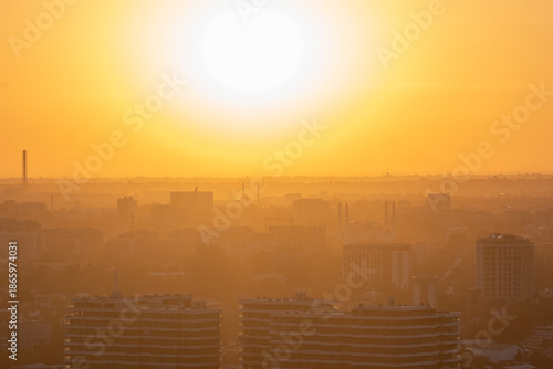 The scene captures a city skyline at sunset. Buildings appear silhouetted against a bright orange and yellow sky. Tashkent, Uzbekistan 09/10/2025