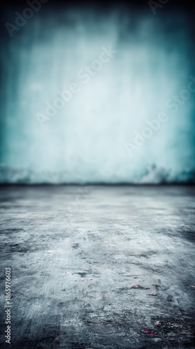 Grunge concrete floor extending into a blurred blue textured wall creating an abstract background