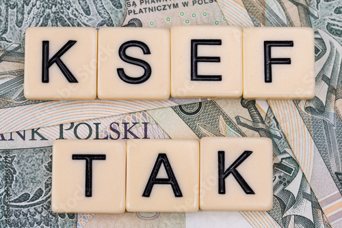Blocks with the abbreviation TAK KSEF, standing for positives about National E-invoice System, are placed against a background of loosely spread Polish 100 PLN banknotes. 