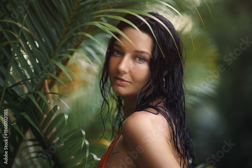 Obraz na plátně Beautiful Woman in Tropical Setting, Wet Hair and Orange Bikini, Lush Greenery