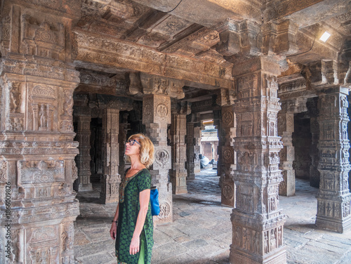 Woman exploring amazing temple complex at Hampi, world famous unesco site. Tourist walking among ruins stone walls gateways in Karnataka, India