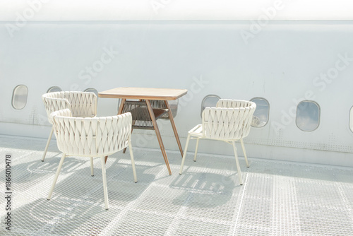 Outdoor cafe, a wooden table and white chairs with beautiful sunlight