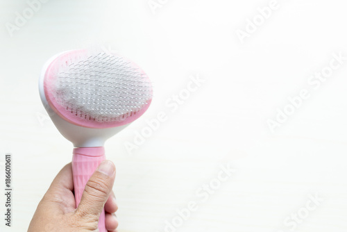 Hand holding a pink grooming cat brush with soft fur