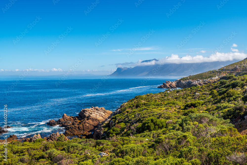Naklejka premium Holiday views of cloud-covered Hottentots Holland Mountains from Clarence Drive, between Gordon's Bay and Rooi-Els, Western Cape, South Africa. Perfect scenic drive for road trips and travel.
