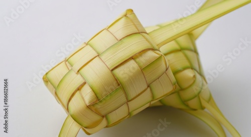 Close-up of two woven, diamond-shaped, pale-green and yellow pouches, on white