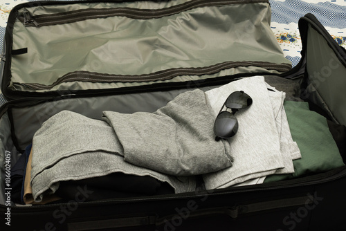 Open suitcase with clothes on bed in room