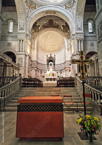Interior altar view of the Basilique Saint-Martin de Tours. Byzantine-Romanesque architecture features intricate mosaics and golden patterns. Soaring dome and massive stone arches
