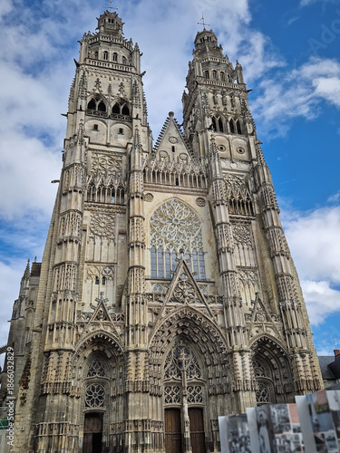 Flamboyant Gothic facade of Tours Cathedral Saint-Gatien in France. The massive stone structure features twin towers, intricate tracery, and a large central rose window. Classic medieval craftsmanship
