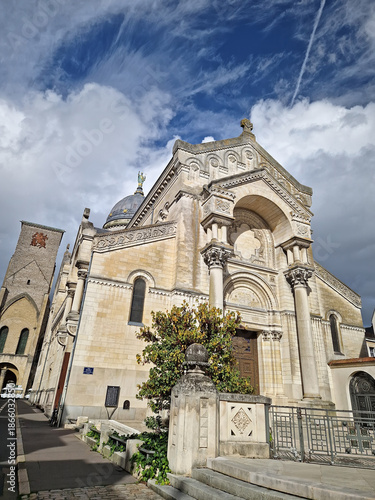Basilica of Saint Martin in Tours, France. Neo-Byzantine church outdoor view of the grand arched entrance, and prominent dome topped with a statue. The medieval Charlemagne Tower stands near the abbey