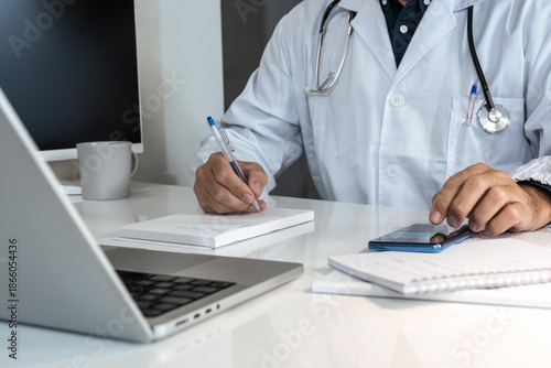 Healthcare professional in lab coat diligently working on a laptop, with stethoscope nearby, representing modern medical practice