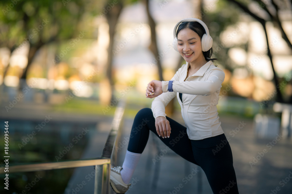 Fototapeta premium Asian woman stretching checking smartwatch in park