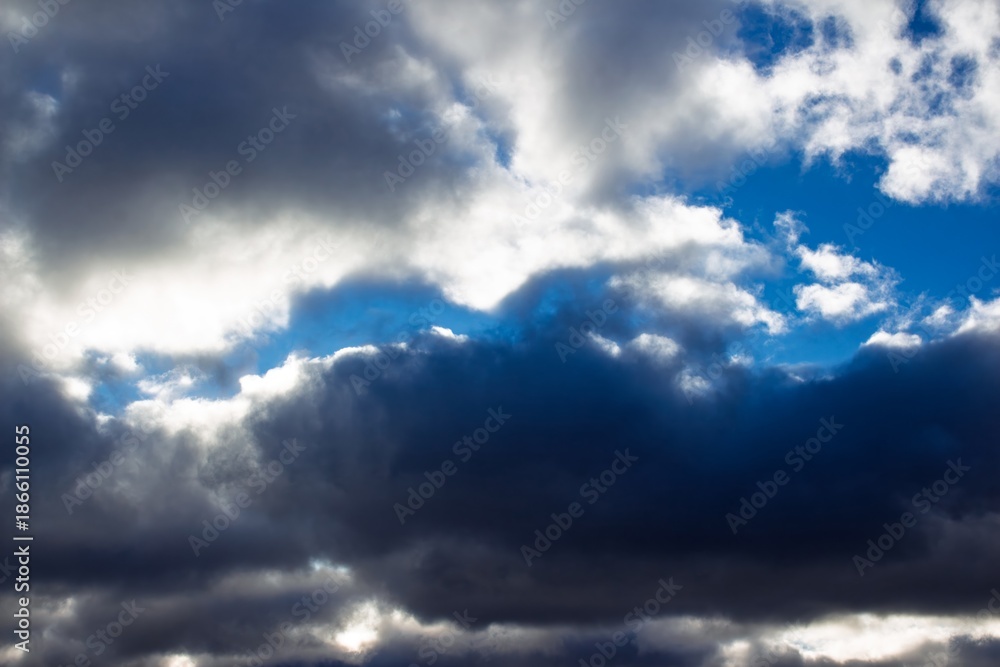 Fototapeta premium Dramatic sky with thick, brooding clouds, sunlight breaking through to reveal brilliant white and deep blue pockets. Powerful, dynamic weather patterns above