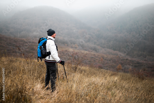 Wallpaper Mural Happy hiker in warm clothing standing in nature with backpack and hiking poles, enjoying a peaceful moment in winter wilderness. Torontodigital.ca