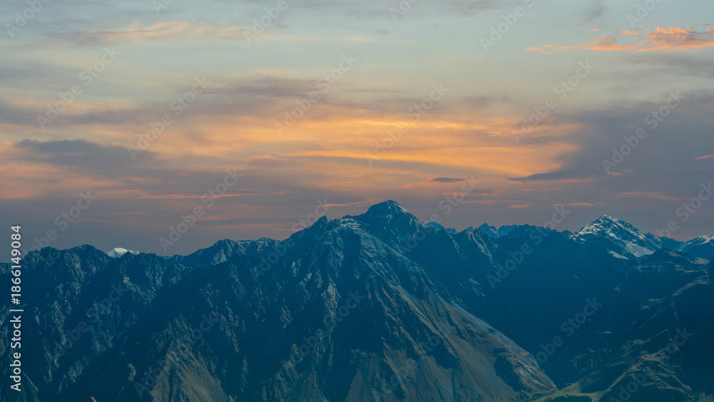 Fototapeta premium Majestic mountain range under warm sunset sky with dramatic evening light.