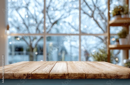 Wooden table in front of a large window with out-of-focus winter scene and shelves