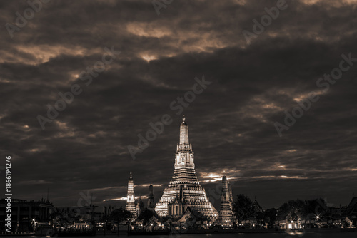 An abstract, blurred background of nighttime lights along the Chao Phraya River in Bangkok, with Wat Arun, a popular tourist attraction visited by travelers from around the world, in the background.