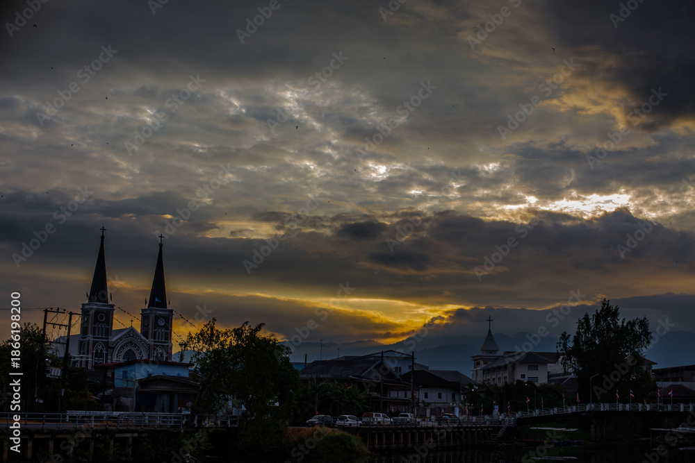 Obraz premium The backdrop of colorful sky lights reflecting off the beautiful river surface at different times of the day, amidst a stunning Christian church in Chanthaburi, Thailand.