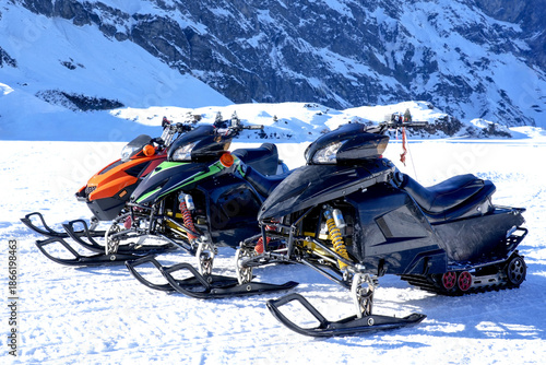 Принти на полотні Three colorful snowmobiles parked on a snowy landscape, showcasing vibrant desig