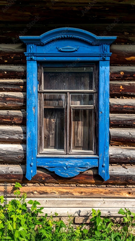 Naklejka premium Window with Blue Carved Frame on Old Wooden Log House