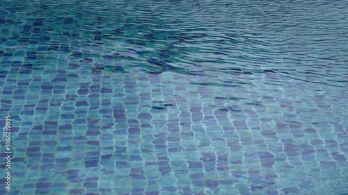 Footage of calm swimming pool water with gentle ripples over blue mosaic tiles,creating a relaxing abstract background.Clean, refreshing texture ideal for summer,wellness, resort,and luxury concepts.
