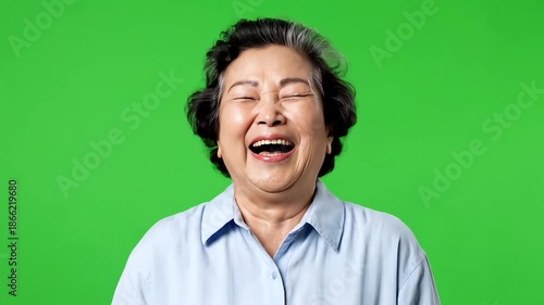 Smiling Asian senior woman in light blue shirt on green background