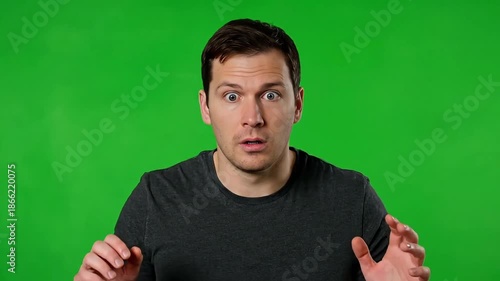 Man expressing surprise and shock with hands raised in front of green background