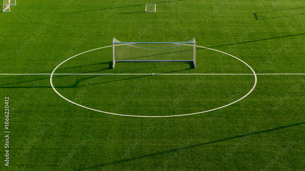 Obraz premium Symmetrical aerial shot of football goal aligned with center circle on artificial turf