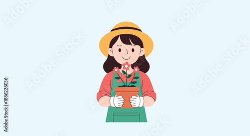 Friendly young woman gardener wearing a hat and apron holding a terracotta pot with blooming red flowers in her gloved hands.