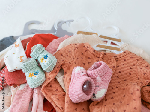 set of stacked organic baby clothes and knitted booties in pastel colors. concept of newborn essentials, baby shower gifts, or eco-friendly infant fashion with a cozy, domestic feel