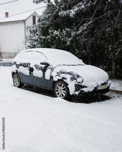 Snow falling on a snow covered car. Snow covers a car. Parked car during a snowfall