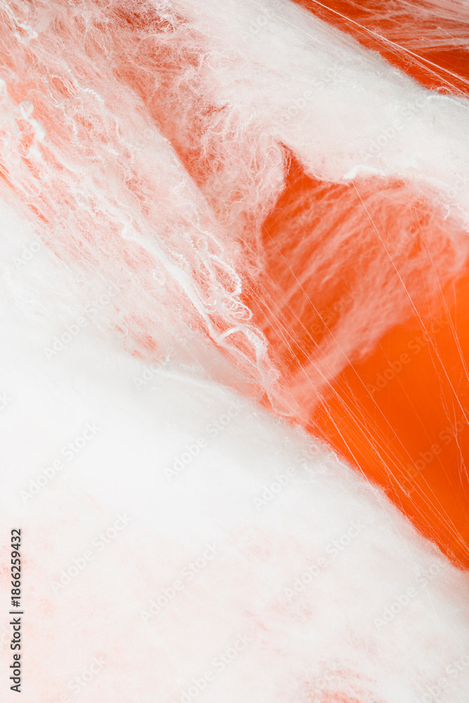 Fototapeta premium Spooky Halloween decoration with white cobweb on an orange background. Mockup, copy space, or template. Perfect for creating a festive atmosphere for Halloween parties or spooky projects