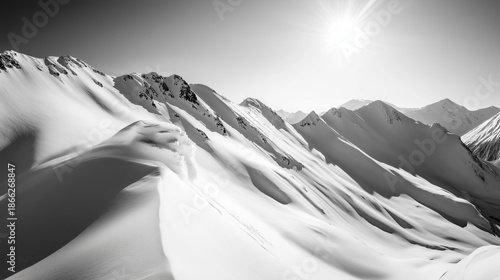 Black-and-white photograph of snowy mountains with sunlight, high contrast, wide-angle view of snow-capped peaks.